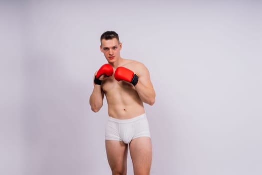 Studio shot of athlete boxer training and practicing jab. Isolated on white studio background. Concept of sport, healthy lifestyle. Red sportswear.