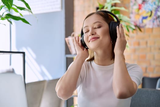 Young happy woman in headphones with closed eyes enjoying music, audio text book. Technology, lifestyle, youth concept