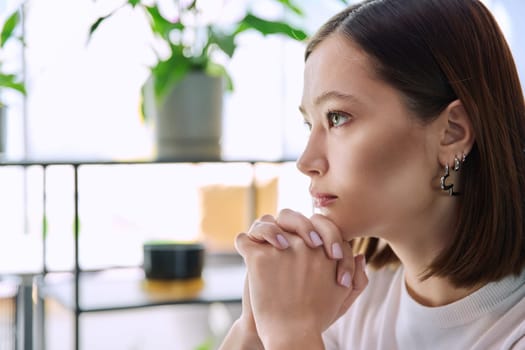 Excited sad upset serious young woman with folded hands, face in profile close-up. Emotions stress depression troubles difficulties, mental health, youth lifestyle concept