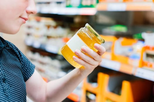 The guy in the supermarket holds glass jar of honey