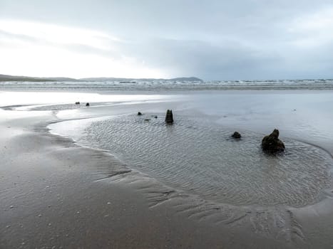 The remains of the unknown shipwreck become visible during the storm at Dooey beach by Lettermacaward in County Donegal - Ireland.
