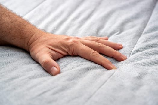 The man checks the quality and softness of the new mattress he will buy by pressing it with his hand