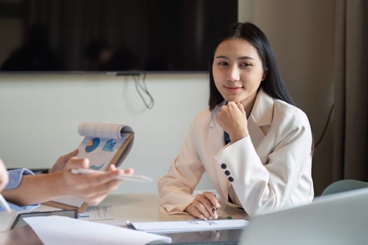 Happy business woman listening to discussion in office boardroom. Business professional sitting in meeting with colleagues.