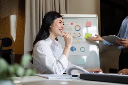 Happy business woman listening to discussion in office boardroom. Business professional sitting in meeting with colleagues.