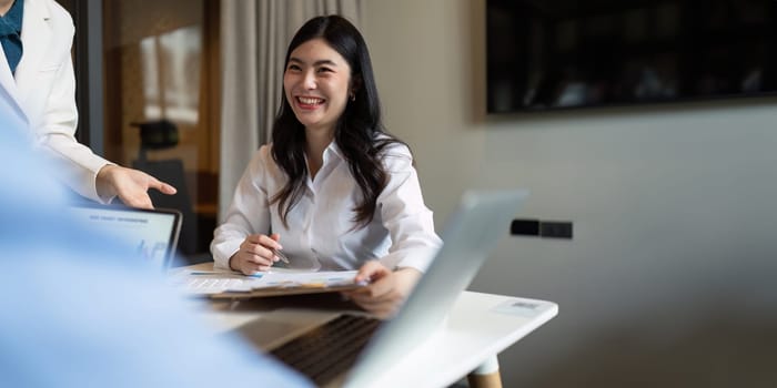 Happy business woman talking and discuss in office boardroom. Business professional sitting in meeting with colleagues.