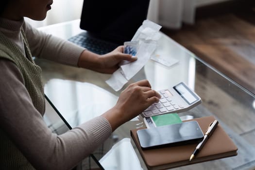 young woman calculate finance, hand holding mobile phone and invoice paper, pay from bills tax.