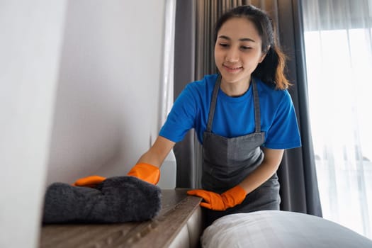 Cleaning service woman cleans dust on the headboard with a cloth. House cleaning service concept.