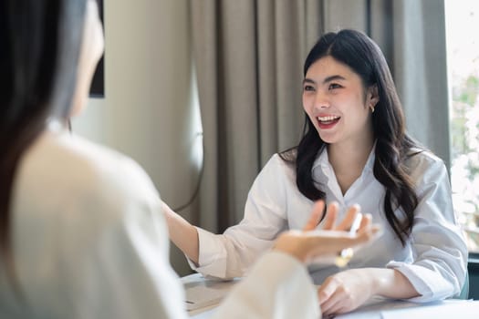 Happy business woman talking and discuss in office boardroom. Business professional sitting in meeting with colleagues.