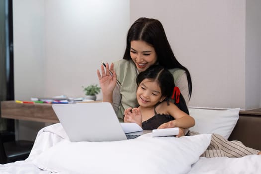 Work from home, freelance and lifestyle concept. Portrait of creative asian female sitting on bed with laptop and her take care of her kid while working.