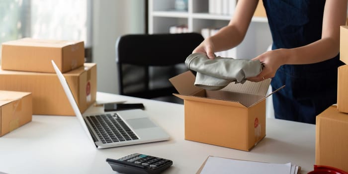 Asian business owner working at home with packing box of her online store prepare to deliver product to customers, sme business ideas online concept.
