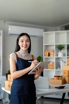 Young business woman asian working online ecommerce shopping at her shop. Young woman sell prepare parcel box of product for deliver to customer. Online selling.