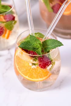 Summer Sangria cocktail or lemonade with raspberry, orange and mint. Refreshing organic non-alcoholic, Detox vitaminized healthy drink, fruit in a in a glass. Quench your thirst on a hot day.