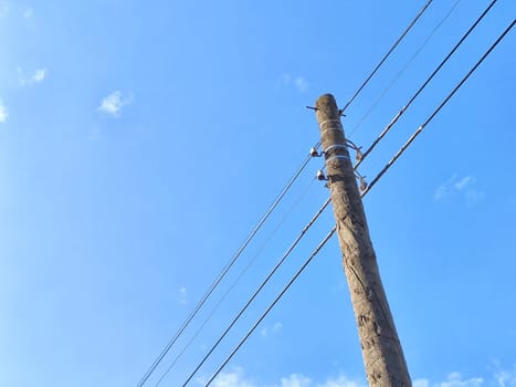 Old power line pole against blue sky in a nice sunny day