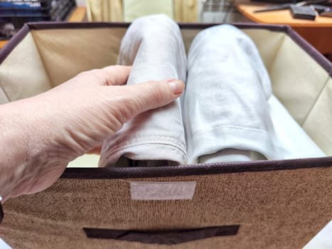 Organized Clothing Storage Using Konmari Folding Method. Neatly folded clothes arranged vertically in a storage box