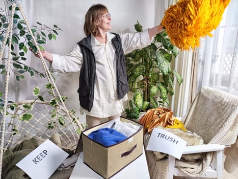 Middle-Aged Woman Sorting Belongings With KonMari Method. Mature woman categorizes items into keep and discard piles