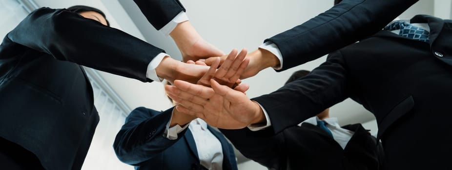 Office worker team stacking hand together symbolize successful group of business partnership and strong collective unity teamwork in community workplace in panoramic banner. Shrewd