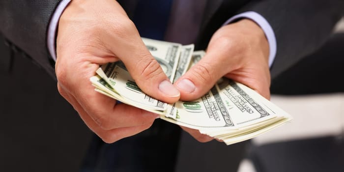 Man in suit and tie hold in arm pack of hundred dollar bills closeup. Stock market exchange earn pile rich present gift employer prepayment service gratitude concept