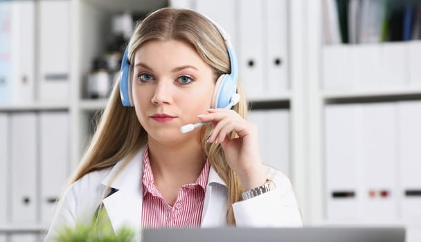 A beautiful feminine blonde doctor talking to patient over wireless headset advises a medical problem the formation of remote education internship callcenter specialist