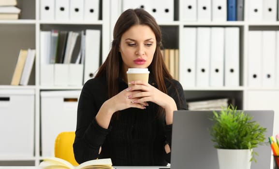 Beautiful brunette smiling clerk woman work with laptop pc computer hold in arm plastic cup of tea portrait. White collar clerk worker workplace job offer web chat wireless social net concept