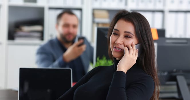 young pretty brunette woman in office work with her boss hold smartphone in hands talk to partners