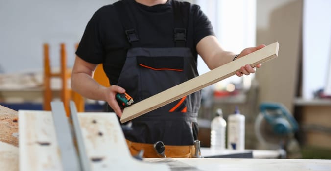 Portrait of a smiling carpenter holding wood planks in a construction site