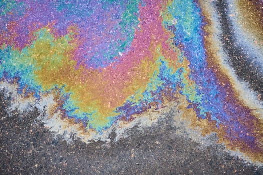 Texture of colorful petrol oil spill on wet pavement.