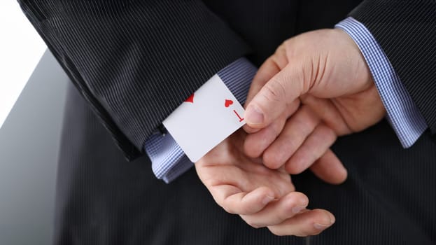 Close-up of cheater hands pulling ace card out of sleeve with crossed arms behind. Gamer with strong addiction to games. Bribe casino and dishonesty concept