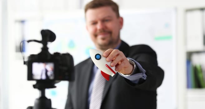 Businessman hold rocket in hand closeup on office background business concept