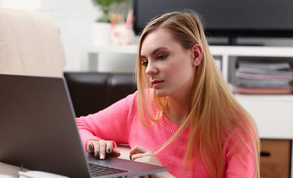 young beautiful blond woman sit in livingroom work on laptop pleasant weekends concept