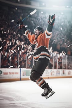 A hockey player in a yellow jersey leaps joyfully after scoring a goal, with the crowd cheering in the background