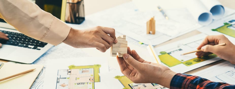 Professional engineer and architect collaborate on eco house project at meeting table with green design blueprint and architectural equipment at modern office. Focus on hand. Close up. Delineation.