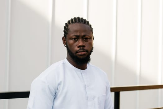 Cheerful male tourist dress in white wear dashiki ethnic smiling at city street on stairs. African American travel model have free time.