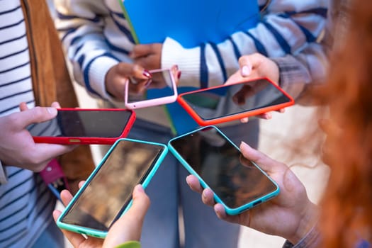 Group of friends using looking at their smartphones Multiracial teenagers browsing the internet with mobile phone on campus