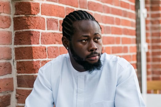 Close up portrait of a happy african american man smiling wearing ethnic dashiki clothes outdoor in summer street colourful brick wall. Millennial generation student and youth. Copy space.