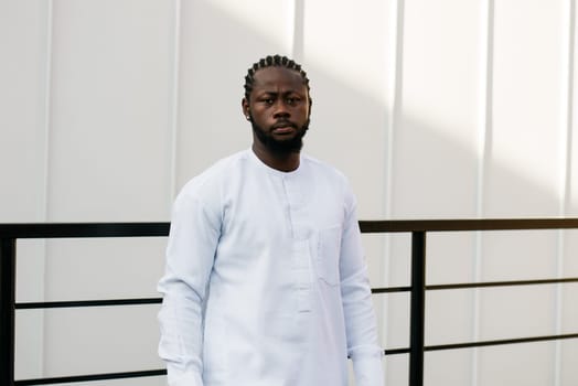 Close up portrait of a happy african american man smiling wearing ethnic dashiki clothes outdoor in summer street colourful brick wall. Millennial generation student and youth. Copy space.