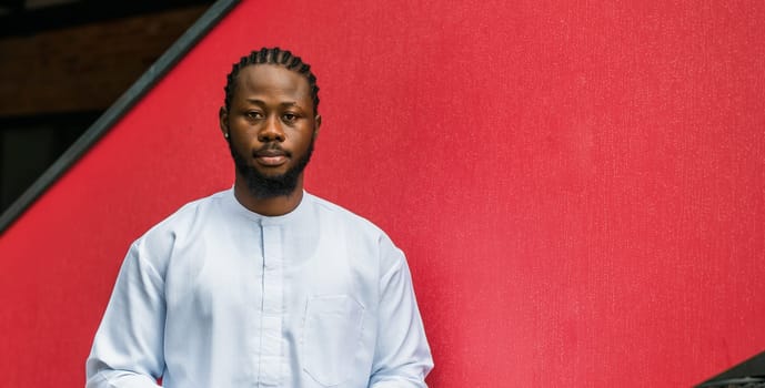 Banner portrait of a happy african american man smiling wearing ethnic dashiki clothes outdoor in summer street wall. Millennial generation student and youth. Copy space.