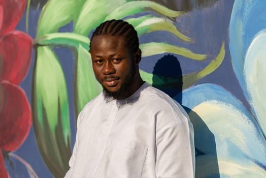 Close up portrait of a happy african american man smiling wearing ethnic dashiki clothes outdoor in summer street wall.