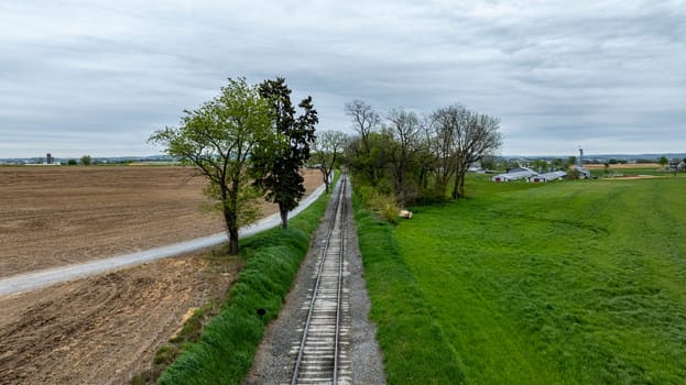 A train is traveling down a track next to a field. The train is black and steam is coming out of the front