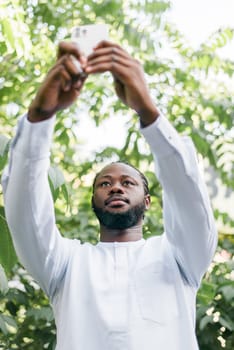 Happy young African American man in dashiki ethnic clothes taking selfie on brick wall background. Millennial generation student and youth