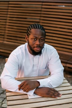 Close up portrait of a happy african american man smiling wearing ethnic dashiki clothes outdoor in summer cafe terrace background. Millennial generation student and youth