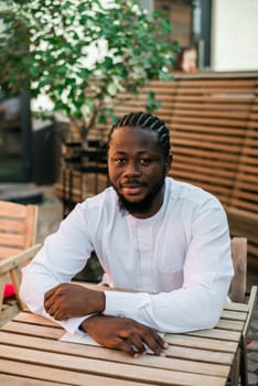 Cheerful male tourist portrait dress in white wear dashiki ethnic smiling at city street or small town background. African American travel model have free time. Millennial generation and gen z people.