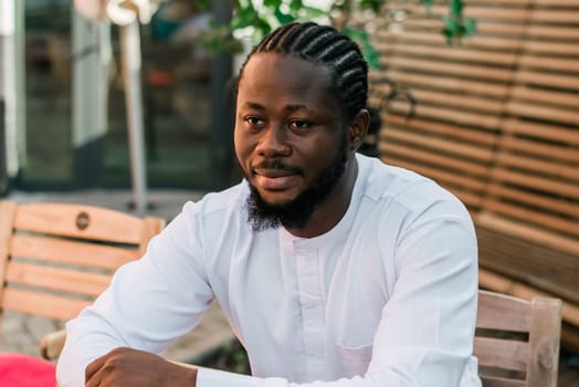 Close up portrait of a happy african american man smiling wearing ethnic dashiki clothes outdoor in summer cafe terrace background. Millennial generation student and youth