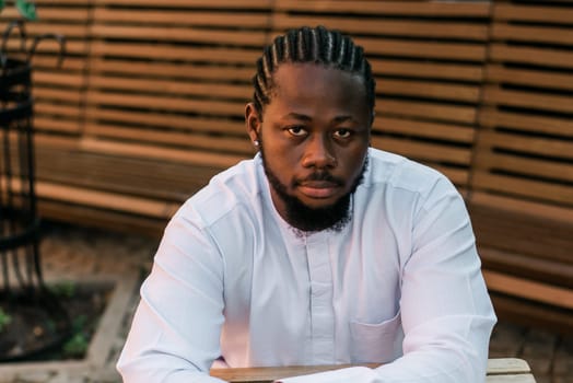 Close up portrait of a happy african american man smiling wearing ethnic dashiki clothes outdoor in summer cafe terrace background. Millennial generation student and youth