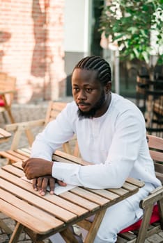 Cheerful male tourist portrait dress in white wear dashiki ethnic smiling at city street or small town background. African American travel model have free time. Millennial generation and gen z people.