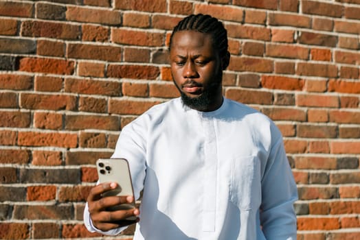 African american man checks cell phone in the street cafe in summer day. Millennial generation and gen z people. Social networks and dating app