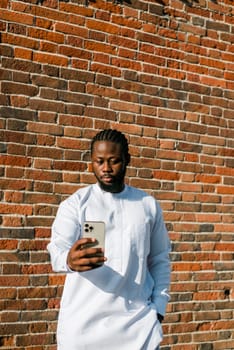 African american man checks cell phone in the street cafe in summer day. Millennial generation and gen z people. Social networks and dating app