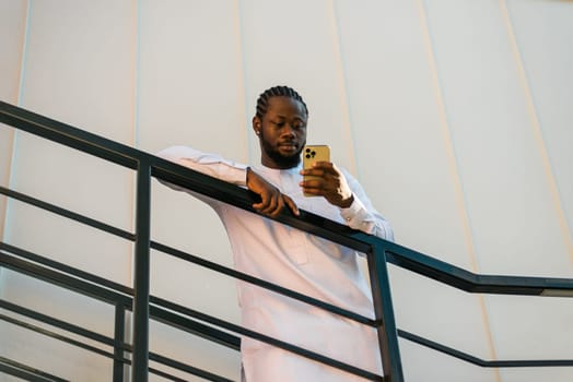 African american man checks cell phone in the street cafe in summer day. Millennial generation and gen z people. Social networks and dating app