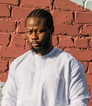 Close up portrait of a happy african american man smiling wearing ethnic dashiki clothes outdoor in summer street wall. Millennial generation student and youth. Copy space.