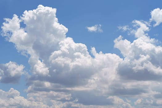 A plane soaring through a sky filled with fluffy white clouds on a sunny day.