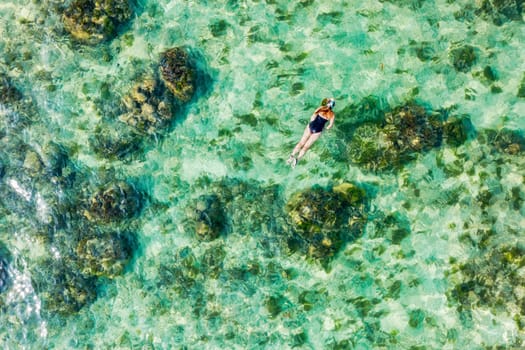 Aerial view of unrecognizable women snorkelling in tropical waters. Aerial view around a young women snorkeling above coral reef reaching deeper parts of the crystal clear water, Mauritius.